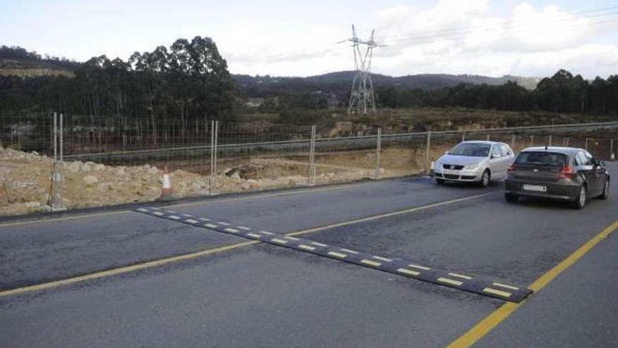 Dos coches circulan junto a una banda reductora de velocidad instalada en el vial del polígono de Morás.