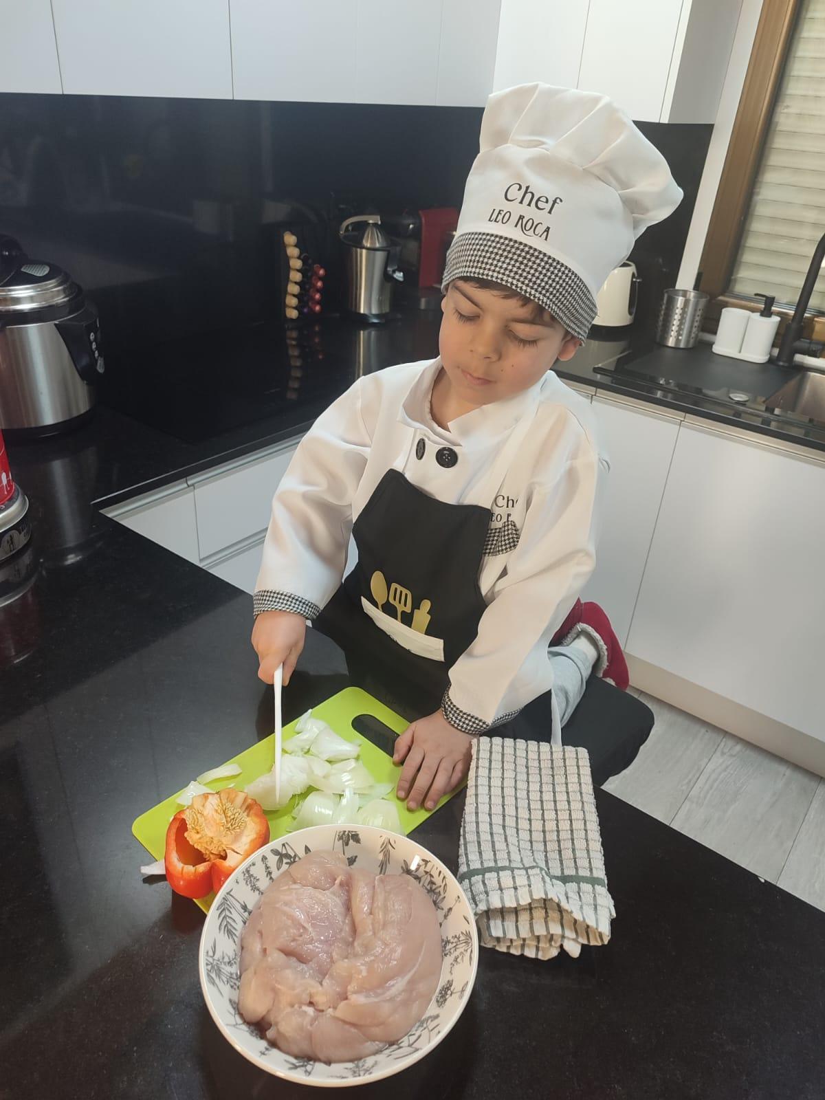 Leo Roca Sánchez, cocinando en su casa subido a un taburete.