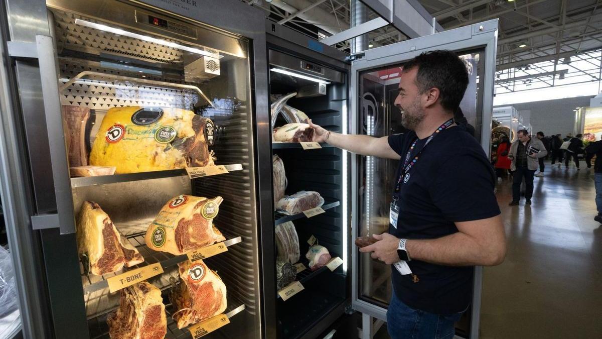 Un trabajador junto a una nevera donde se exponen diversos cortes de carne.