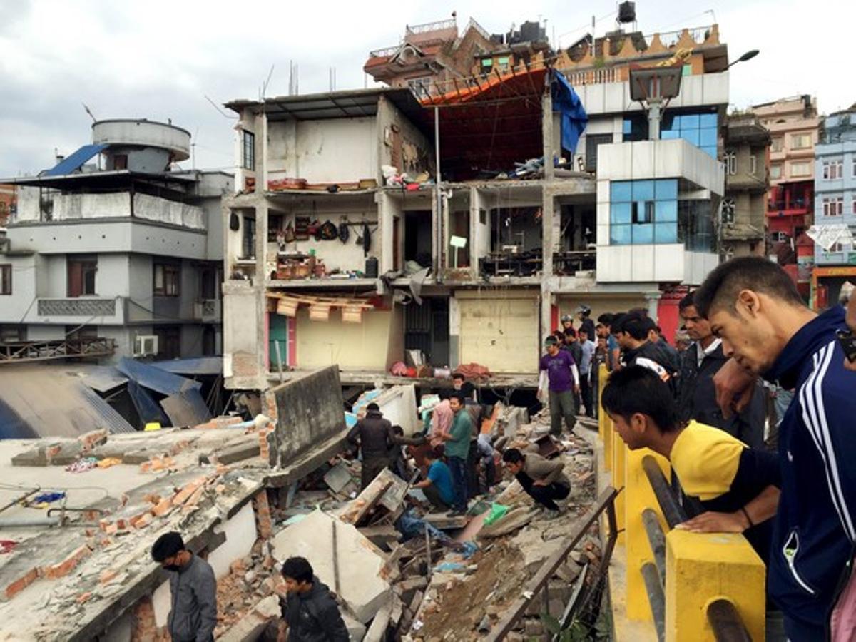 Un grupo de personas observa un edificio derrumbado en Katmandú.