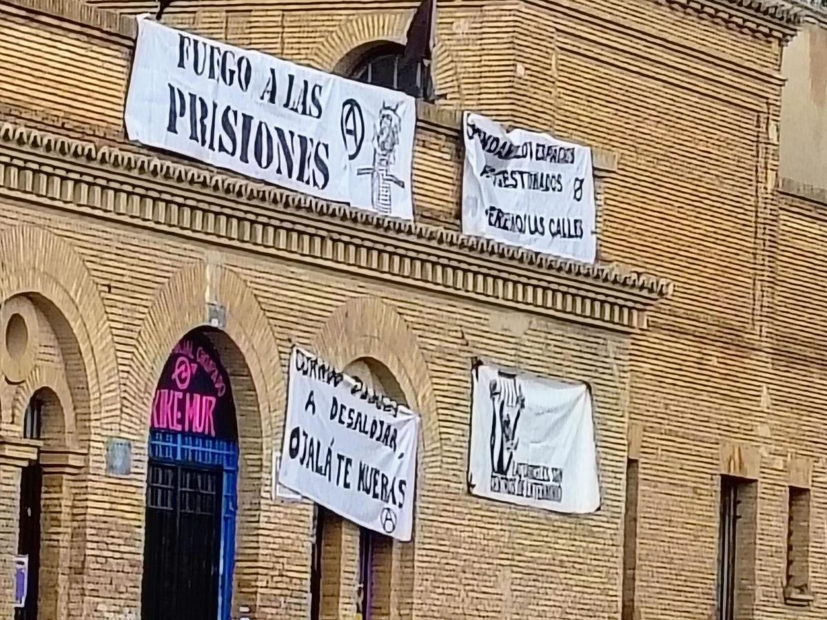 Pancartas con amenazas a la entrada de la antigua cárcel de Torrero, okupada desde hace años.