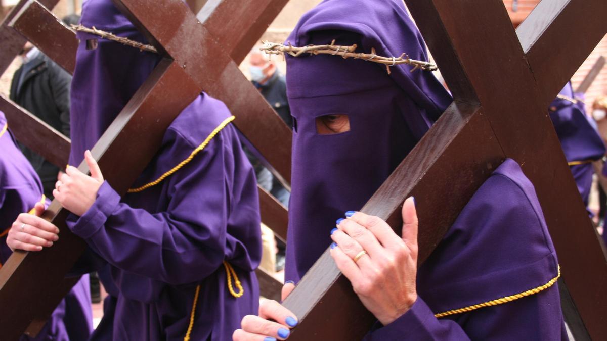 Penitentes con la cruz a cuesta camino del Calvario, custodiado por el Paso Morado.