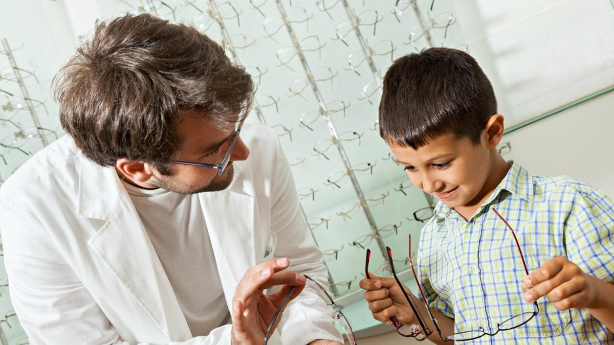Un niño elige unas gafas en una óptica.