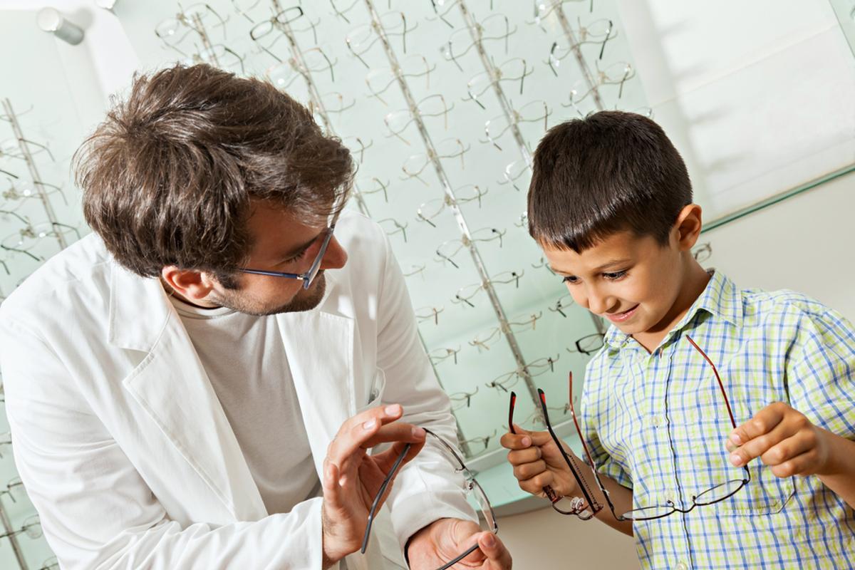 Un niño elige unas gafas en una óptica.