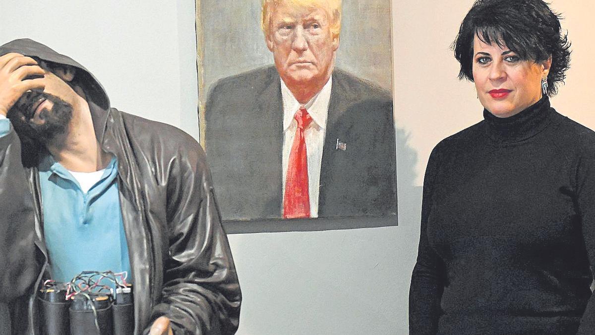 Eva Hernández posa ante el retrato de Trump y la escultura de un kamikaze.