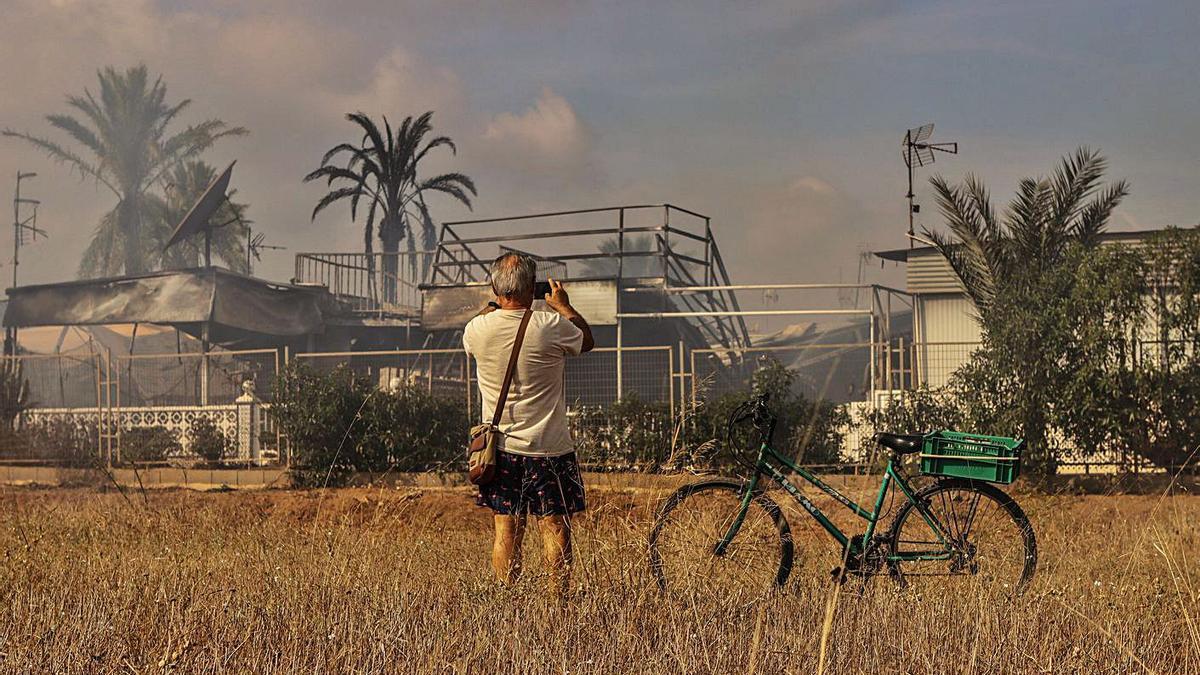 Un hombre fotografía los daños que causó el incendio en el Caravaning La Manga. | LOYOLA PÉREZ DE VILLEGAS