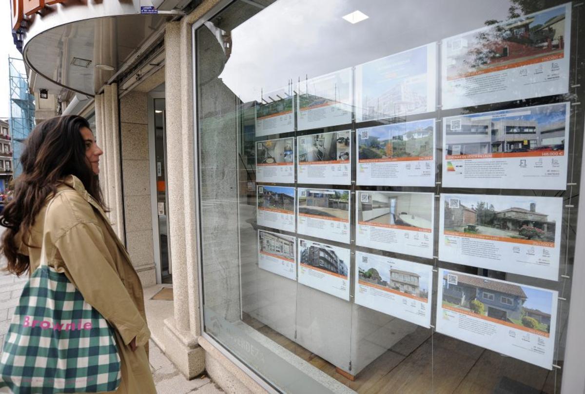 Una mujer observa el escaparate de una inmobiliaria. | BERNABÉ/JAVIER LALÍN