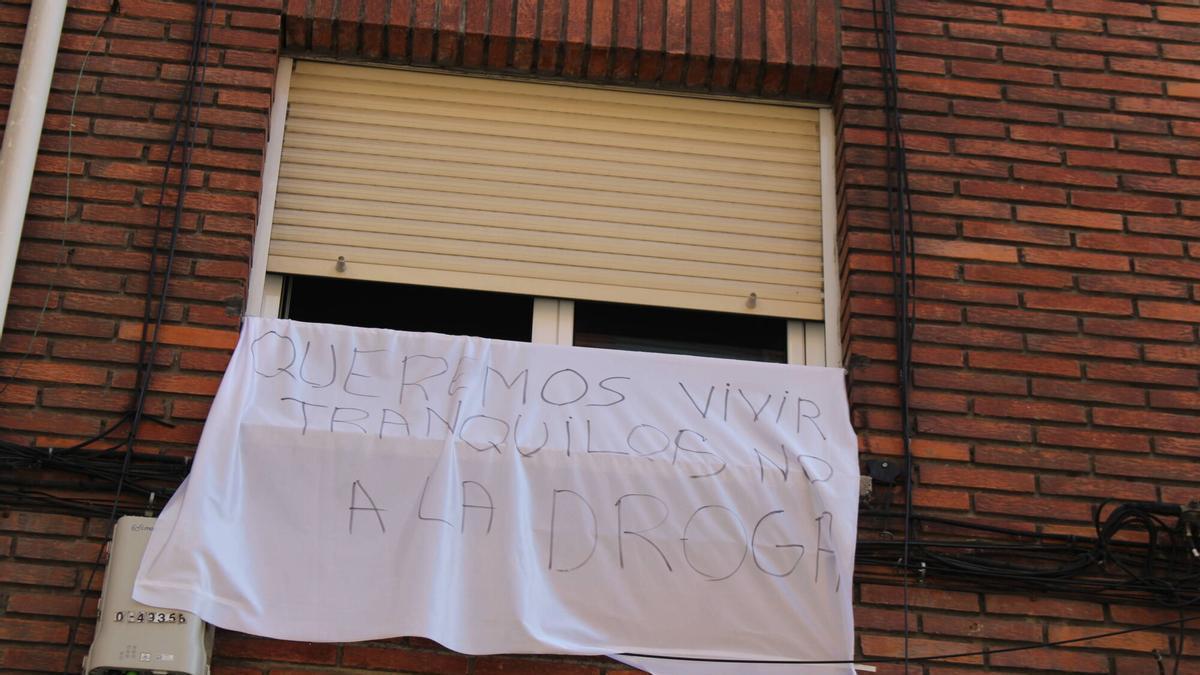 Detalle de uno de los pisos con una pancarta denunciando la situación en la Avenida de Sama.
