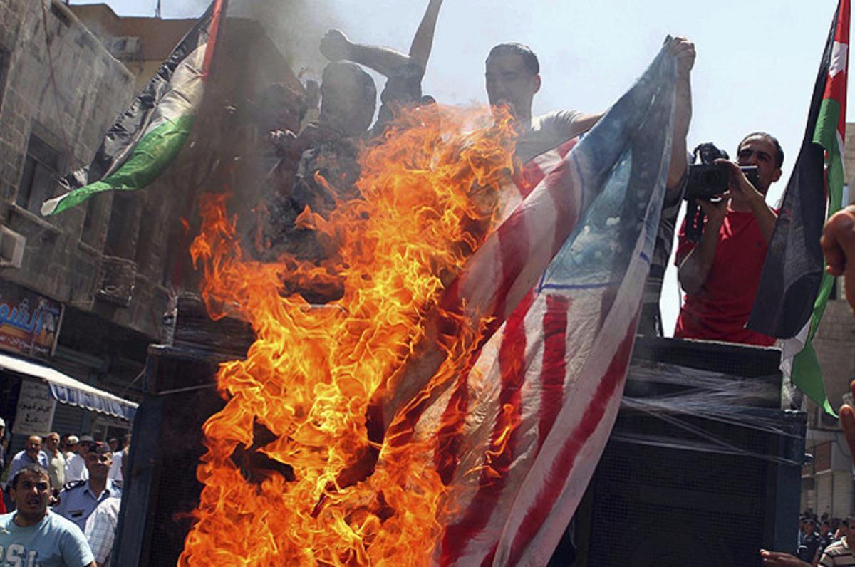 Diversos jordans cremen una bandera dels Estats Units durant una protesta contra el Govern, al centre d’Amman.