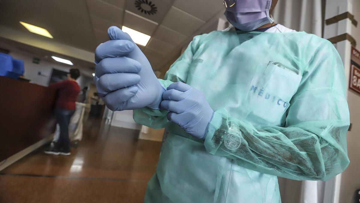 Un profesional médico en un hospital con bata, mascarilla y guantes en una foto de archivo.