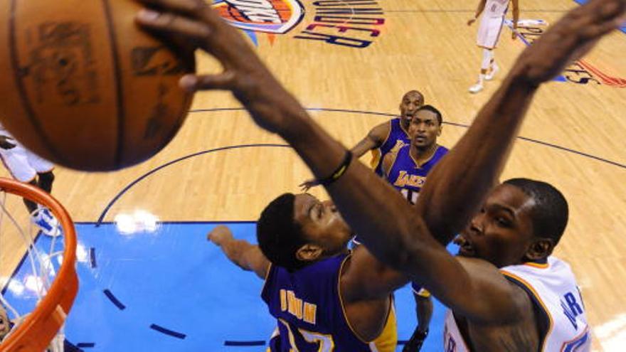 El jugador de Thunder Kevin Durant (d) convierte una cesta ante la marca de Andrew Bynum (c), de Lakers