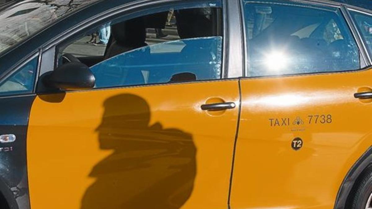 La sombra de un taxista se refleja sobre su vehículo, en cuya puerta figura el identificador del turno T2, el pasado sábado.