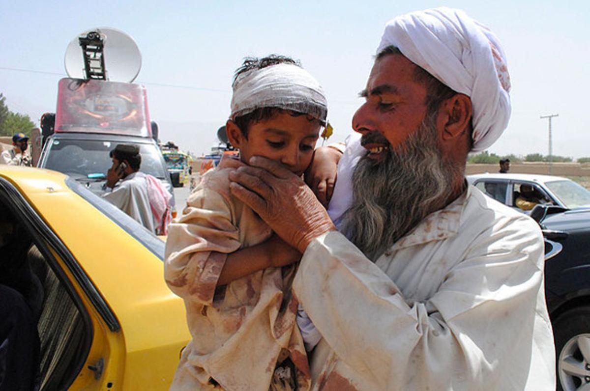 Un home porta un nen a coll després de ser ferit en un atemptat en un autobús a Balutxistan (Pakistan). Sis persones van morir i una vintena van resultar ferides.