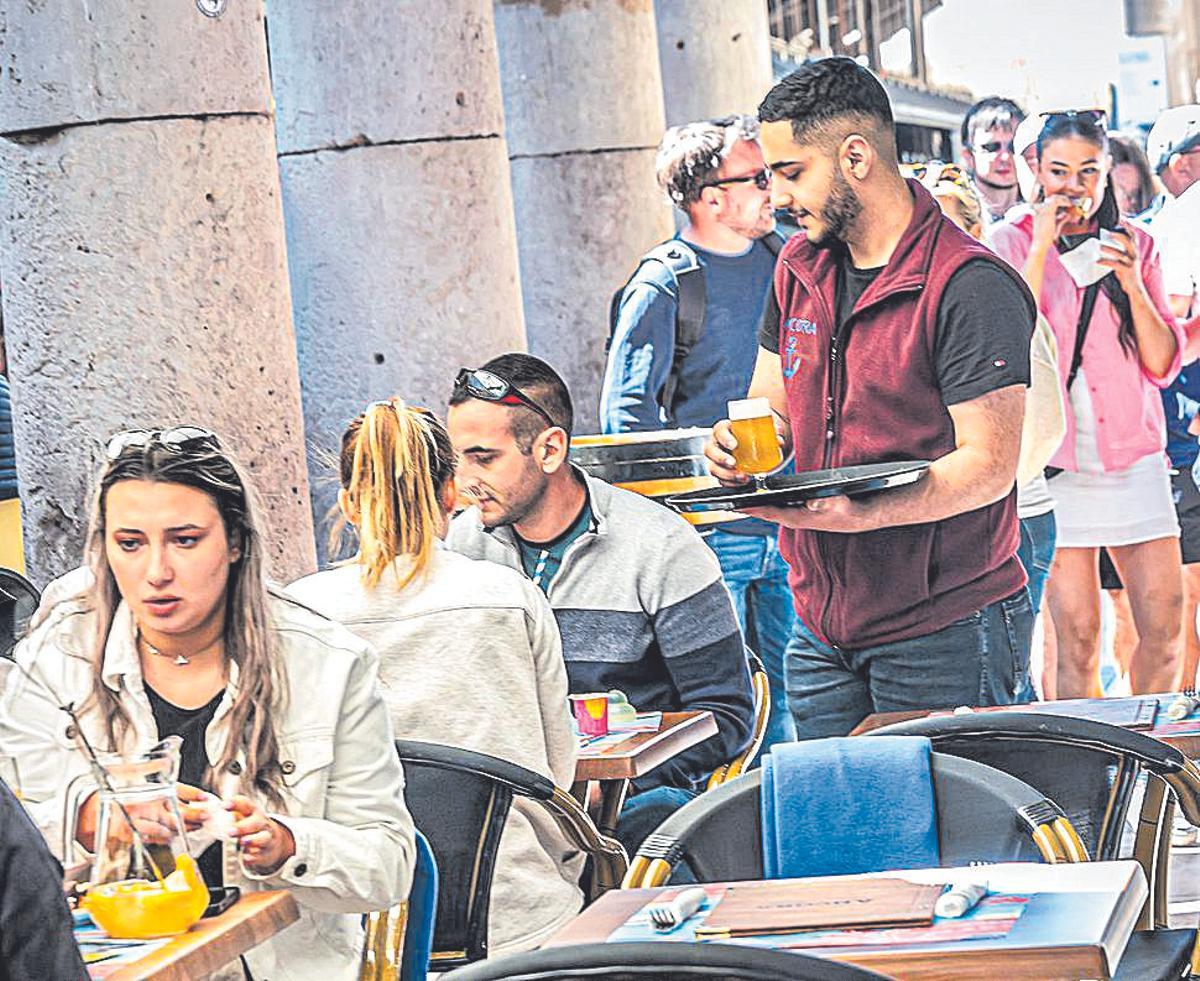 Un joven camarero sirve mesas en Barcelona