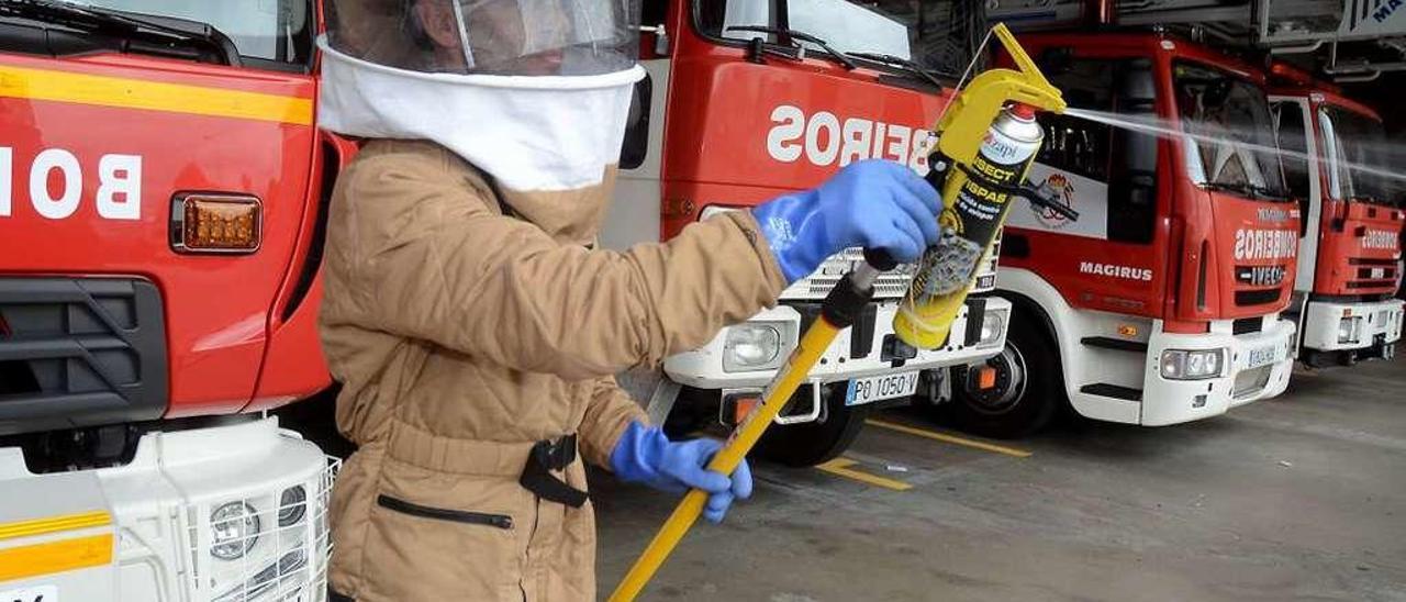 Un bombero, protegido con un traje especial, muestra una de las pértigas fumigadoras. // R. Vázquez