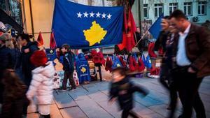 Ciudadanos de Pristina pasean ante banderas de Kosovo y Albania, ayer.
