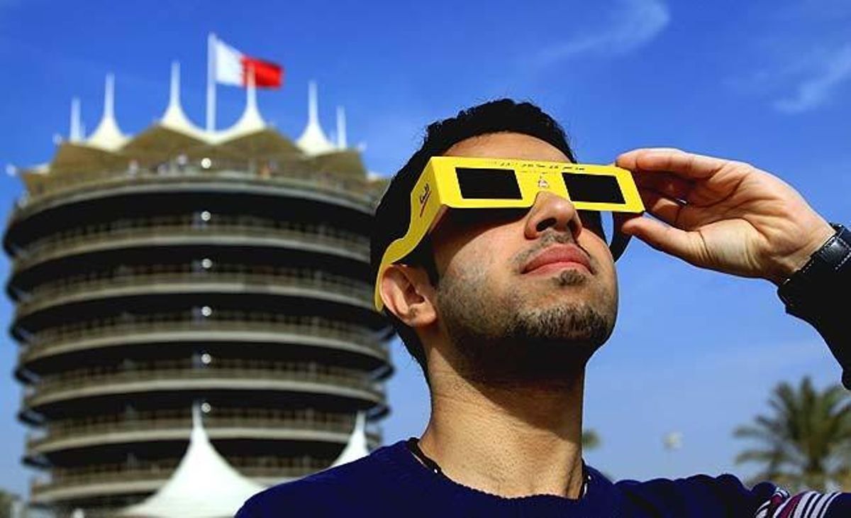 Un jove mira l’eclipsi a prop de la torre del Circuit Internacional de F-1 de Bahrain.