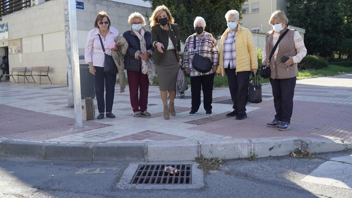 Begoña Medina, la viceportavoz socialista en el Ayuntamiento de Málaga, junto a unas vecinas de la barriada de La Térmica, señala a una alcantarilla obstruida con basura.