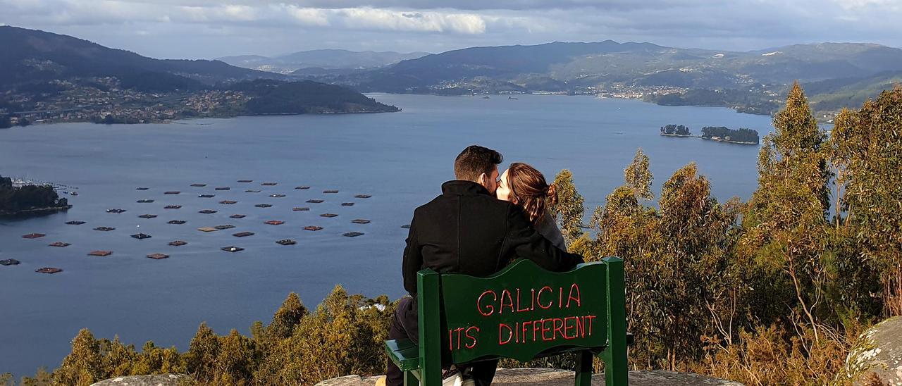 Una pareja de enamorados besándose, con la ría de Vigo al fondo