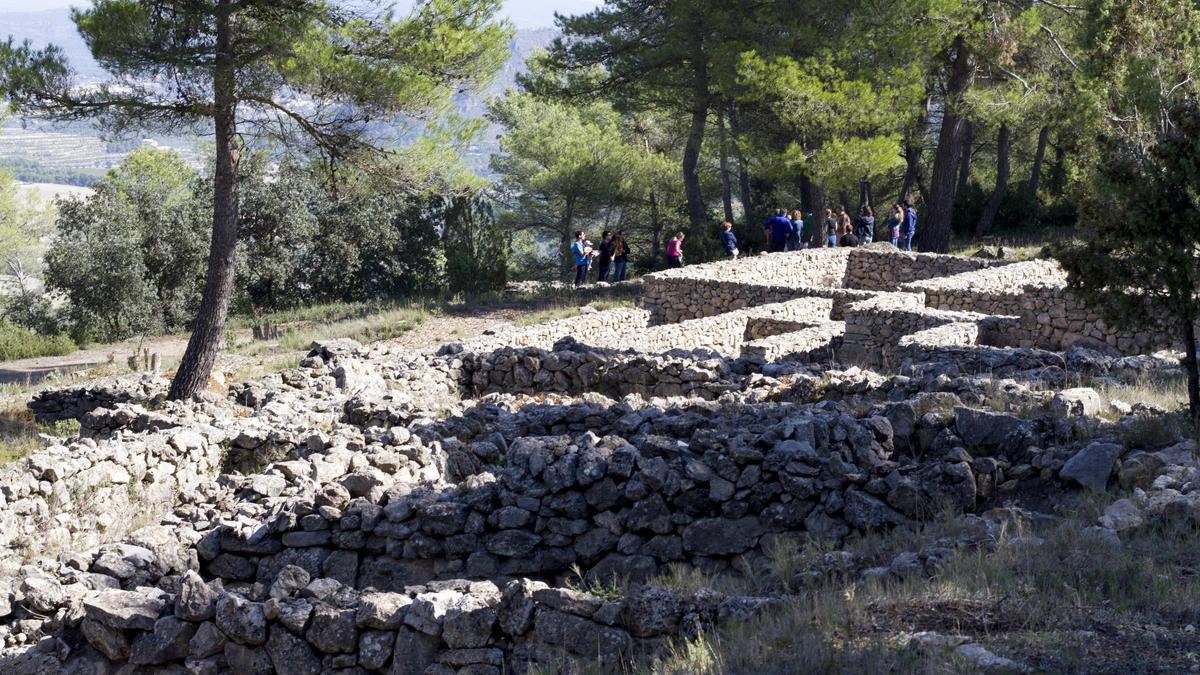 El poblado íbero de la Bastida de les Alcusses y al fondo un grupo de visitantes.