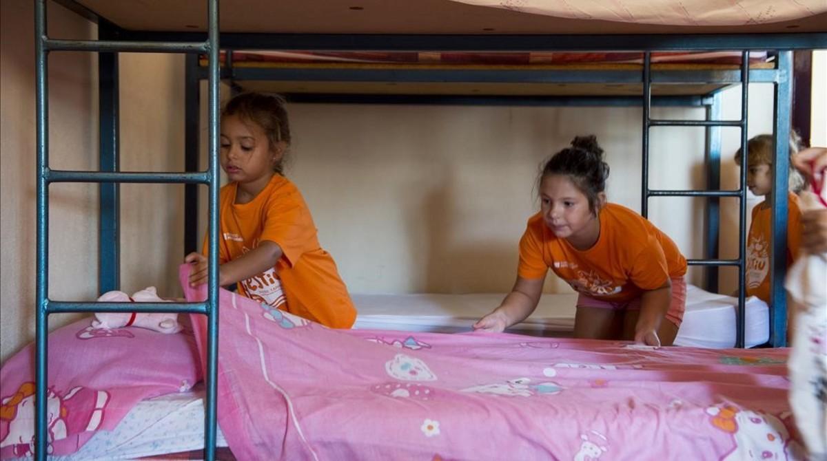 Dos niñas se hacen la cama en la casa de colonias de la Conreria, en Tiana (Maresme), el pasado agosto.