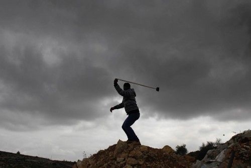 Un palestino utiliza una honda para lanzar una piedra a las tropas israelíes.