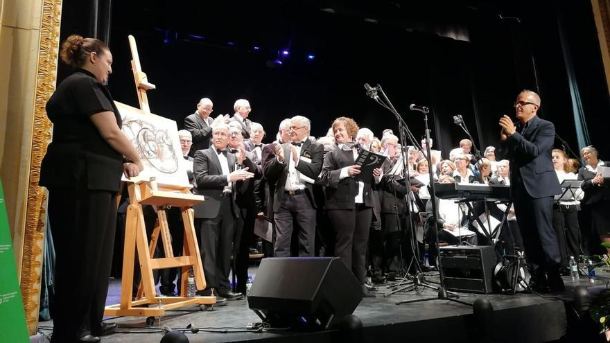 Pozas (izquierda) recibe el aplauso de los músicos de La Mayor tras pintar un cuadro en el concierto. | M. J. C.