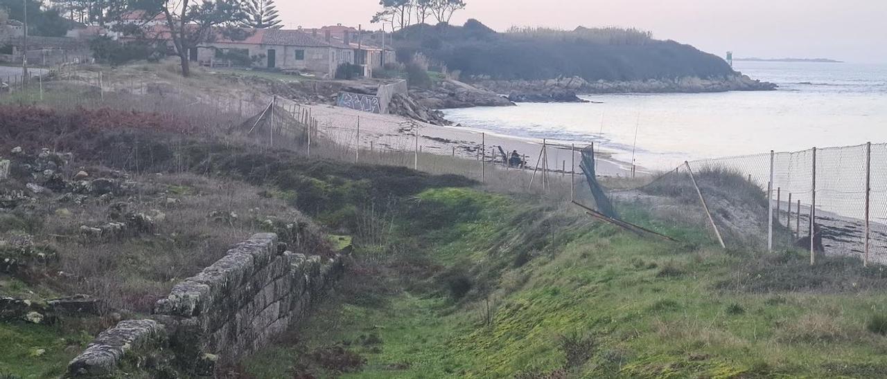 Imagen de Adro Vello en la que se observan su deterioro y la valla perimetral tumbada, la semana pasada. Al fondo, una de las antiguas salazoneras y Punta Castriño.
