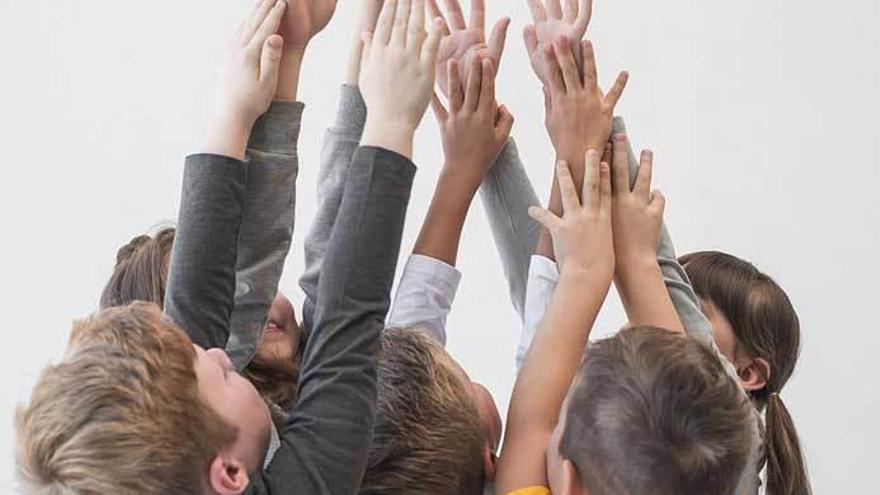 Un grupo de niños con los brazos en alto.