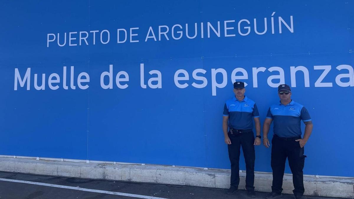 Dos oficiales del puerto posan junto al cartel.