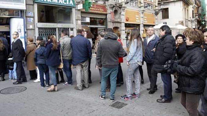 Personas hacen cola ante una administración.