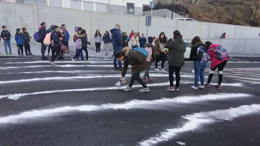 Los alumnos del instituto de Soutomaior, ayer, pintan las líneas del paso de peatones con harina. // FdV