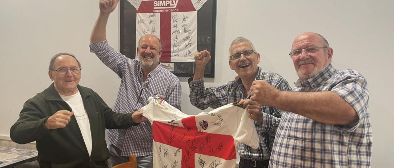 Cuatro aficionados de la SD Huesca sostienen una de las camisetas de su equipo en el bar Reinols, lugar que frecuentan para jugar a las cartas.