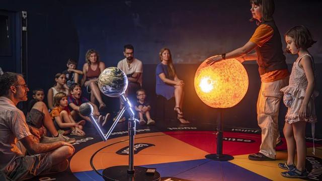 Un grup de nens aprèn com es produeix un eclipsi, en una de les activitats del CosmoCaixa. | MANU MITRU