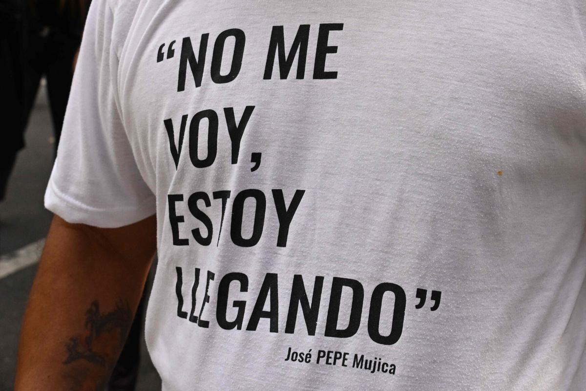 A man wears a t-shirt reading Im not leaving, Im coming -a quote by the late Uruguays former President Jose Pepe Mujica- as the funeral cortege makes its way in downtown Montevideo, on May 14, 2025, a day after his death. Mujica, an ex-guerrilla fighter and hero of the Latin American left, died on May 13, 2025 at the age of 89. The humble leader -- who once spent a dozen years behind bars for revolutionary activity -- lost his battle against cancer after announcing in January the disease had spread and he would stop treatment. (Photo by Eitan ABRAMOVICH / AFP)