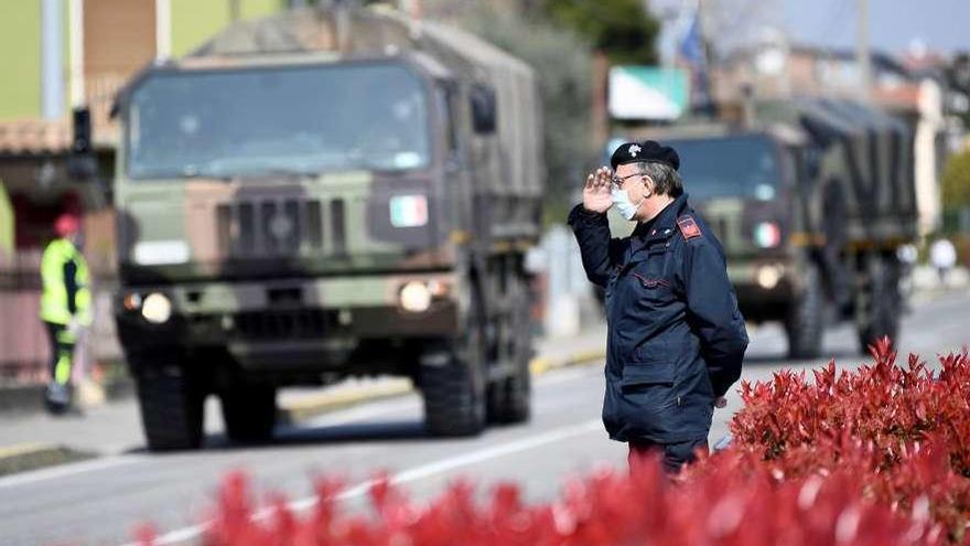 Un carabinero saluda al paso de los camiones con ataúdes en la localidad de Seriate. // Flavio Lo Scalzo