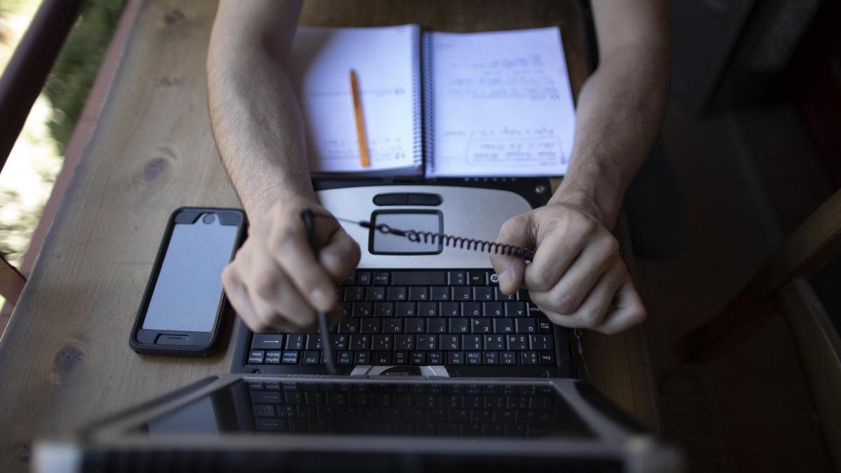 Una persona realiza sus tareas frente a un ordenador portátil.