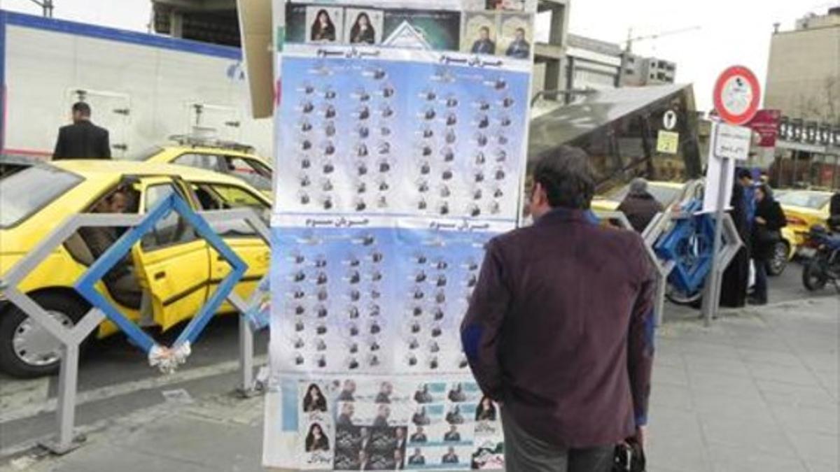 Un iraní contempla un cartel con candidatos a los comicios del viernes.