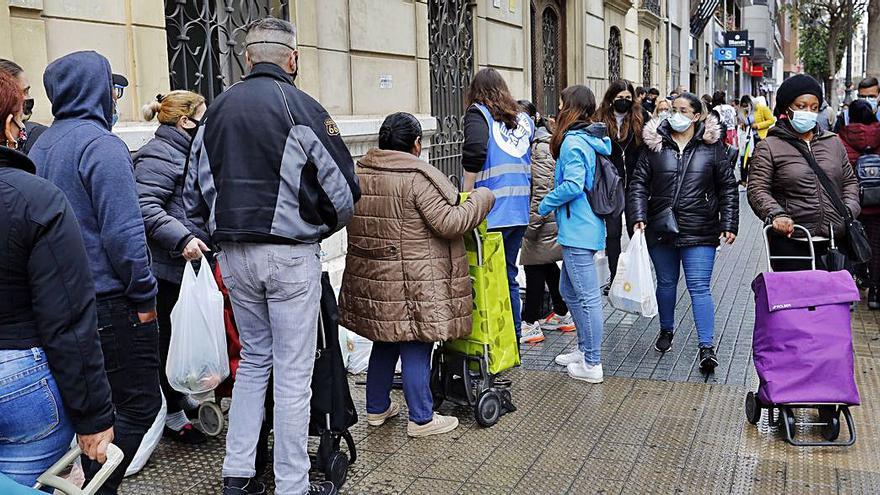 Largas colas para recoger la comida repartida por Esperanza Obrera. | M.A. MONTESINOS