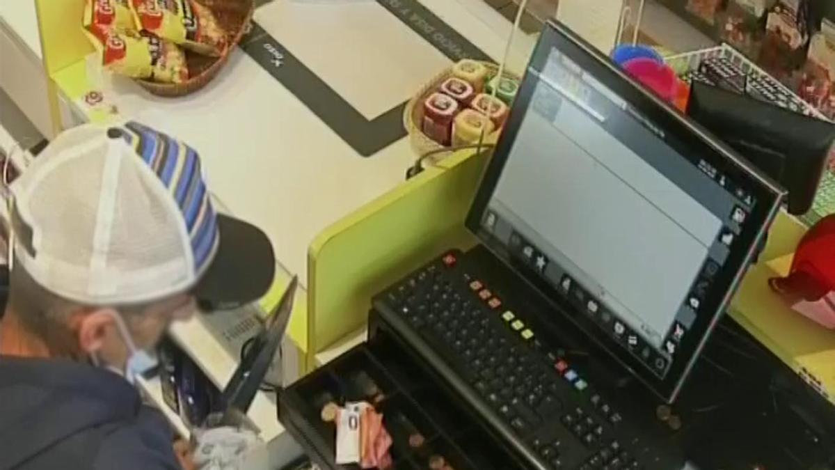 El atracador, con un gran cuchillo, durante el robo en un comercio en Vecindario