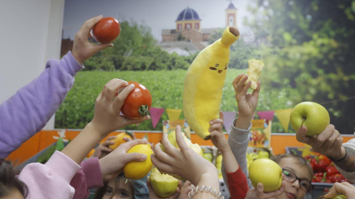 Niños muestran diferentes frutas.