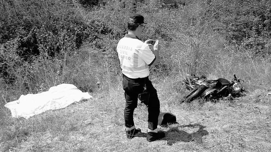 Un guardia civil observa la moto del fallecido (izda.).