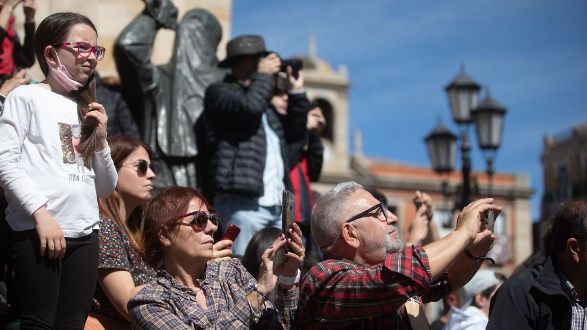 Varias personas graban el paso de la Esperanza por la Plaza Mayor. | Emilio Fraile