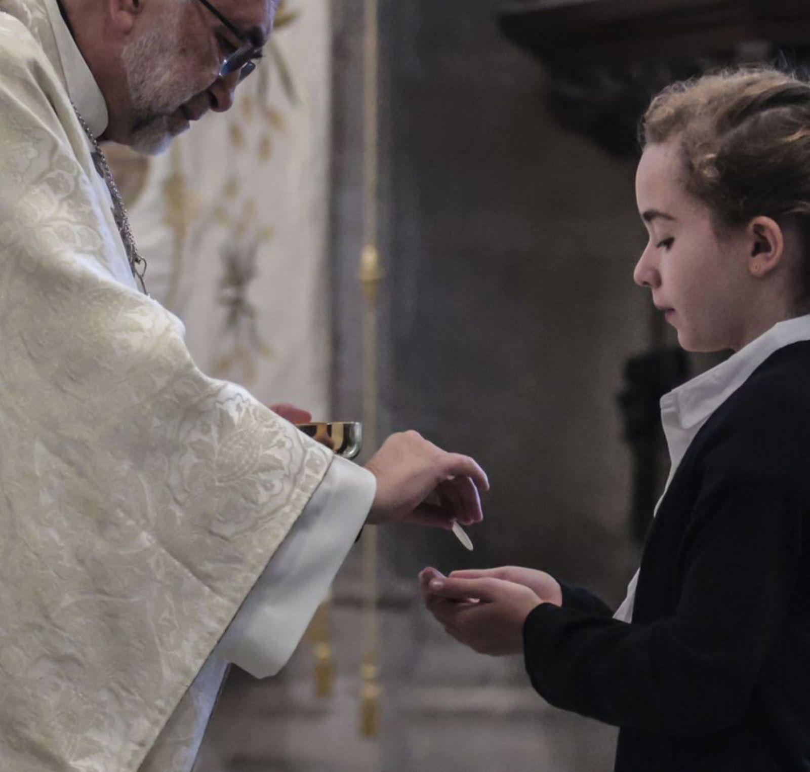 El Arzobispo da la comunión a una niña.