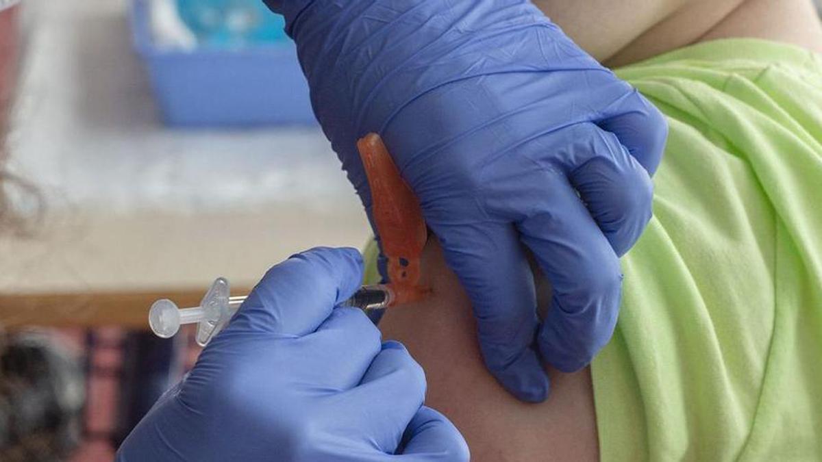 Una infermera injecta una vacuna a un nen