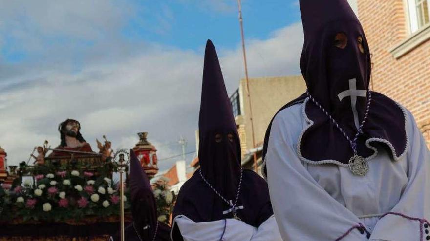 Los cofrades del Santo Ecce-Homo preceden al paso engalanado con flores; a la derecha los nazarenos cargado con la cruz durante la procesión de La Pasión.