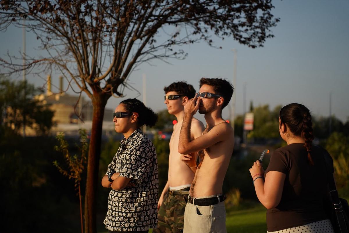Jóvenes viendo el eclipse solar en un parque de Sevilla.