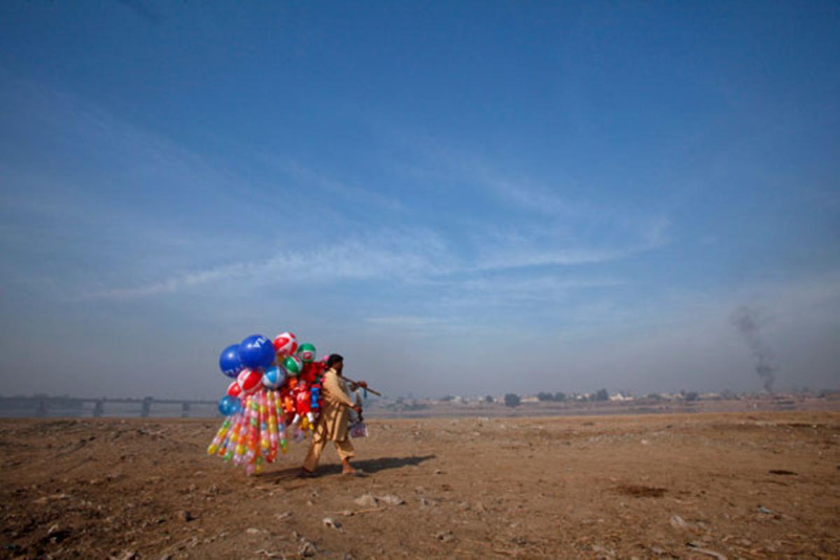 Un home porta globus per vendre’ls a prop del riu Ravi a Lahore (Pakistan).