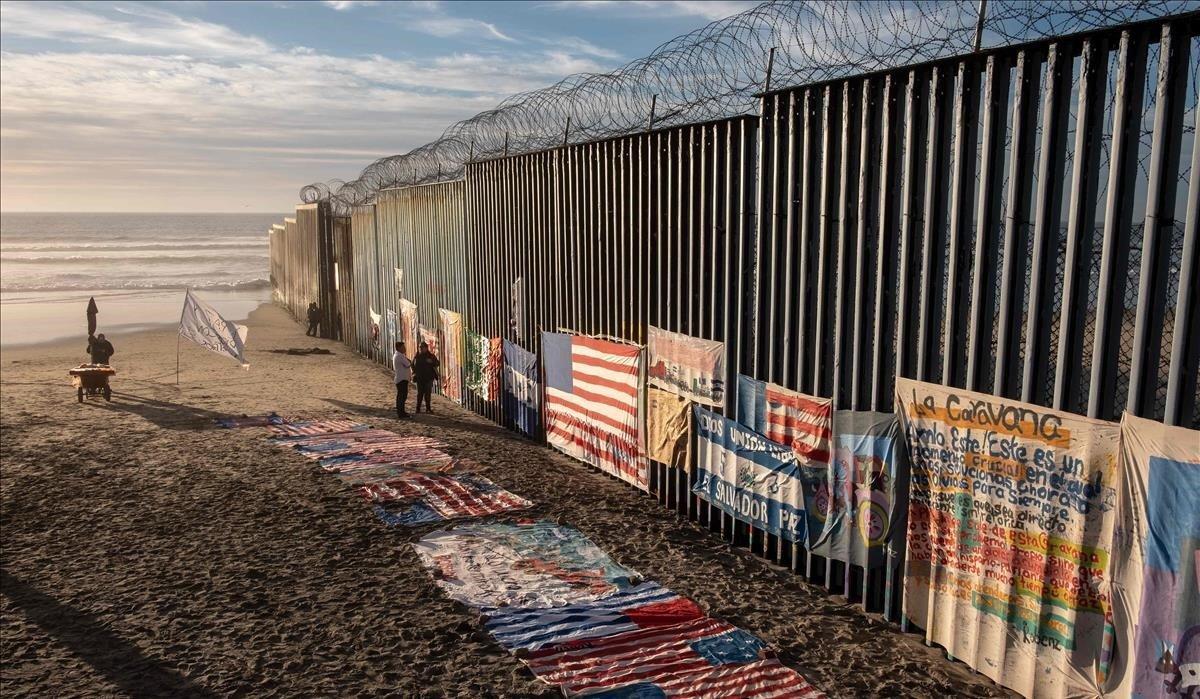 Una exhibición del artista local Robenz y los emigrantes centroamericanos se muestra en la playa al lado de una sección de la valla fronteriza México-Estados Unidos vista desde Tijuana en el estado de Baja California, México.