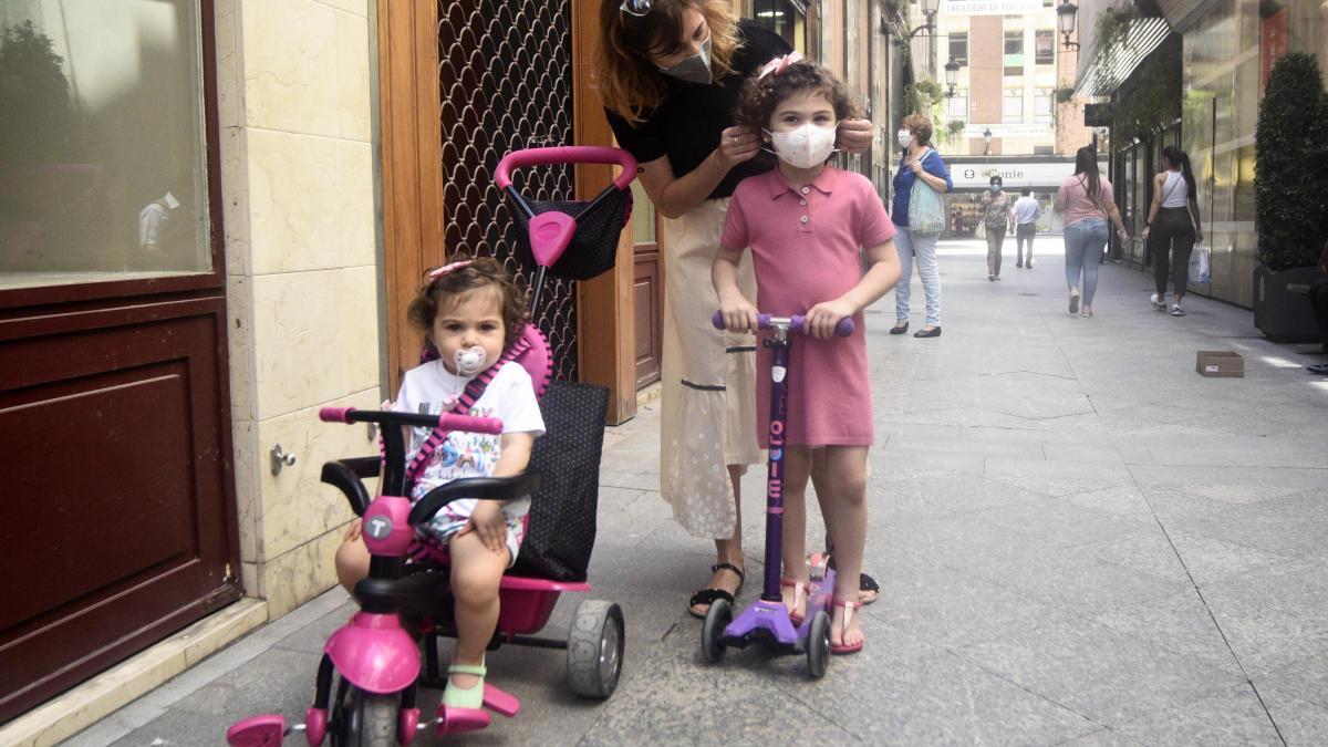 Una mujer le coloca la mascarilla a su hija. israel sánchez